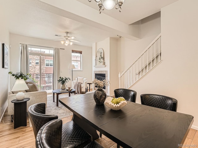 5467 Zephyr Ct Unit 5467, Arvada, CO 80002 - dining space with light wood-type flooring, a tiled fireplace, stairs, baseboards, and a ceiling fan