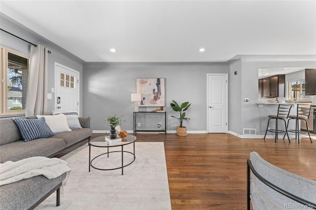 living room with baseboards, wood finished floors, visible vents, and recessed lighting