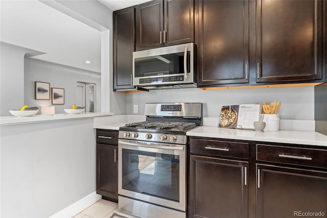 kitchen featuring appliances with stainless steel finishes, dark brown cabinets, light tile patterned flooring, and light countertops