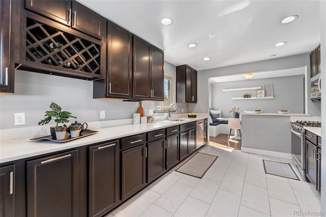 kitchen featuring a sink, dark brown cabinetry, light countertops, appliances with stainless steel finishes, and recessed lighting