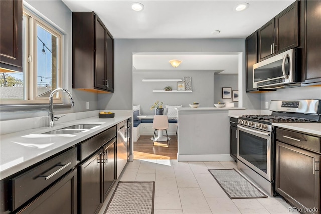 kitchen with recessed lighting, light countertops, a sink, dark brown cabinetry, and appliances with stainless steel finishes