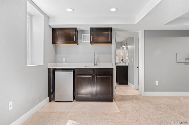 bar featuring a sink, wet bar, baseboards, visible vents, and refrigerator