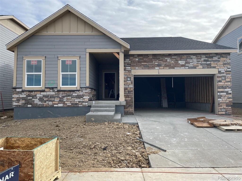 view of front of property featuring stone siding, a garage, board and batten siding, and concrete driveway