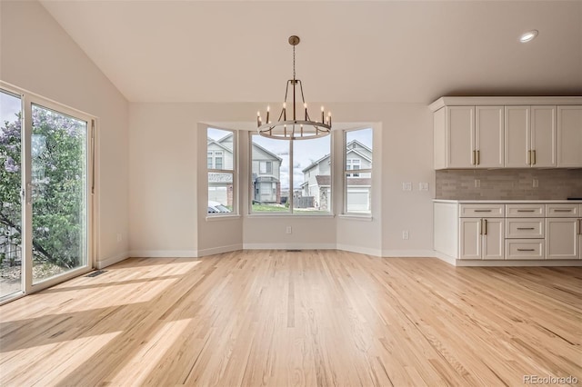 15870 Duckweed Ct, Parker, CO 80134 - unfurnished dining area featuring an inviting chandelier, baseboards, light wood-style flooring, and lofted ceiling