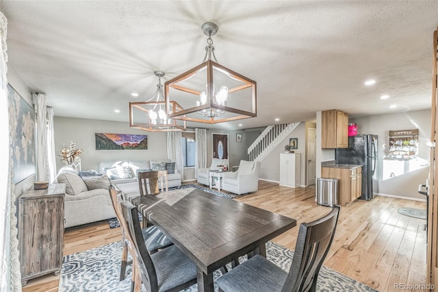 dining room featuring an inviting chandelier, a textured ceiling, and light hardwood / wood-style flooring