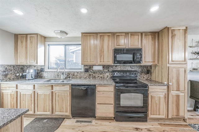 kitchen featuring sink, light brown cabinets, light hardwood / wood-style floors, decorative backsplash, and black appliances