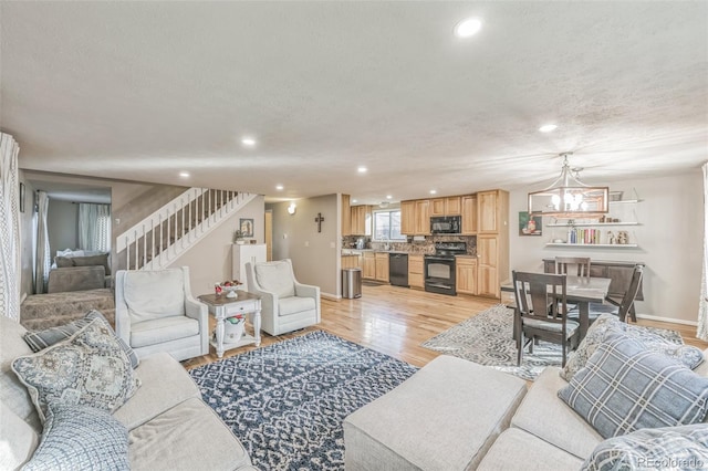 living room with light hardwood / wood-style flooring, a textured ceiling, and an inviting chandelier