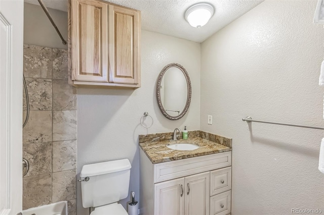 bathroom featuring vanity, a textured ceiling, and toilet