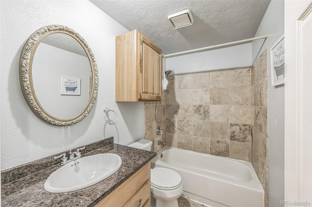 full bathroom featuring tiled shower / bath combo, toilet, a textured ceiling, and vanity