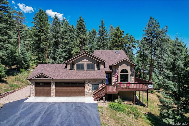 view of front of property featuring a deck, aphalt driveway, an attached garage, stairs, and stone siding