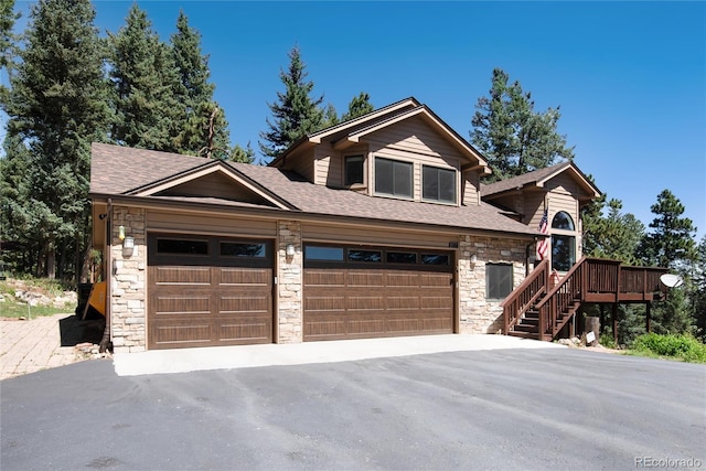 view of front of property with aphalt driveway, stone siding, and a shingled roof