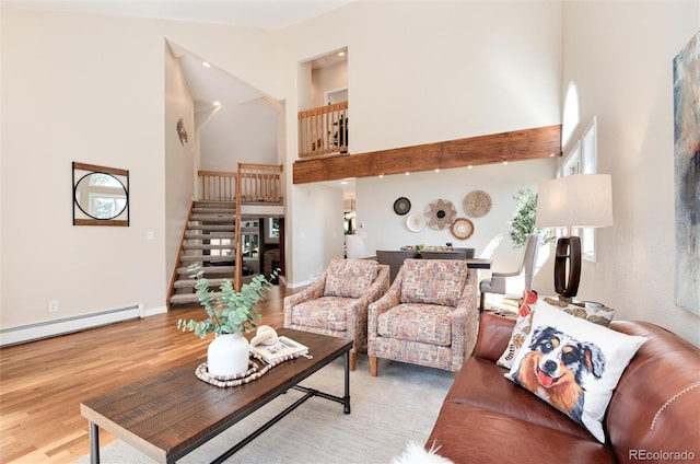 8171 S Homesteader Dr, Morrison, CO 80465 - living area featuring a towering ceiling, stairs, light wood-style flooring, a baseboard heating unit, and baseboards