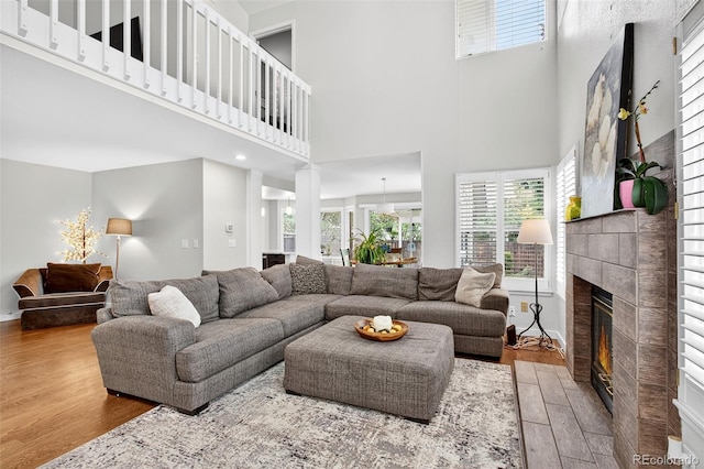 8269 S Gaylord Cir, Centennial, CO 80122 - living room featuring wood finished floors, a high ceiling, a tiled fireplace, and plenty of natural light