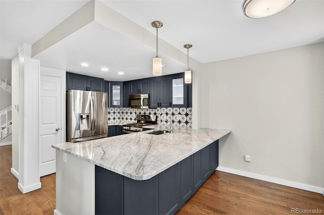 8269 S Gaylord Cir, Centennial, CO 80122 - kitchen with stainless steel appliances, a peninsula, dark wood-style floors, light stone counters, and tasteful backsplash