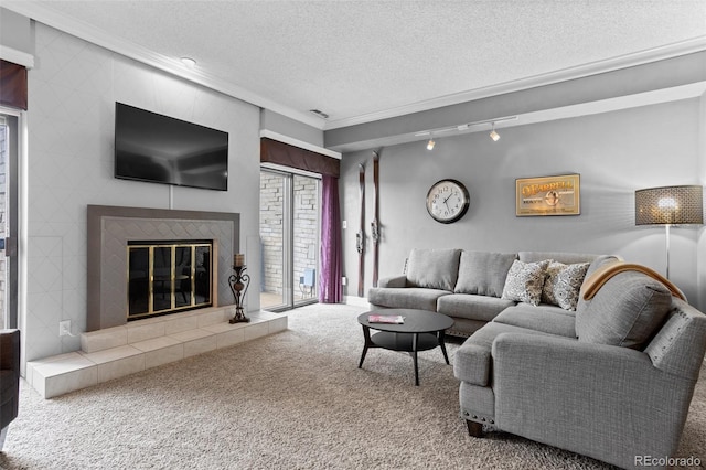 carpeted living room featuring a tiled fireplace, crown molding, a textured ceiling, and track lighting