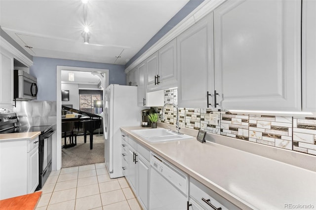 kitchen featuring white appliances, a sink, white cabinetry, backsplash, and light countertops