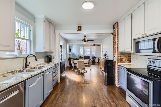 kitchen with appliances with stainless steel finishes, a sink, dark wood finished floors, and white cabinets