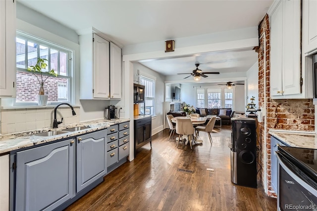 kitchen featuring dark wood-type flooring, a sink, white cabinetry, open floor plan, and backsplash