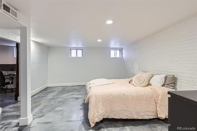 bedroom with baseboards, visible vents, concrete floors, and brick wall