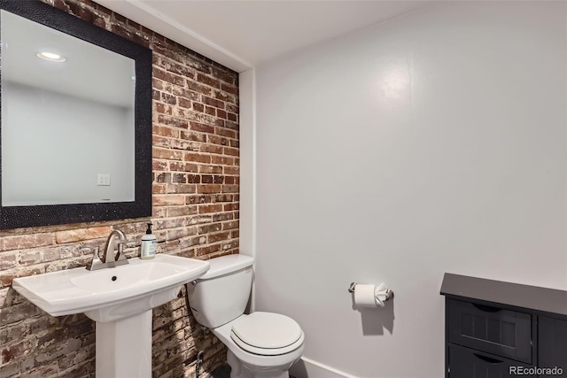 bathroom with brick wall and toilet