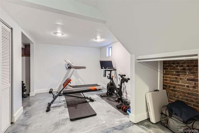 workout area featuring brick wall and baseboards