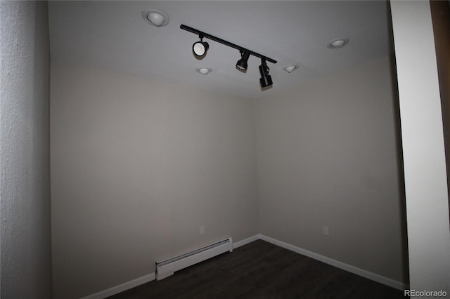 spare room featuring track lighting, dark wood-type flooring, and a baseboard radiator