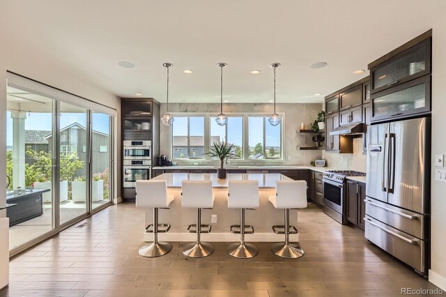 4526 Colorado River Dr, Firestone, CO 80504 - kitchen featuring stainless steel appliances, under cabinet range hood, a center island, open shelves, and a breakfast bar