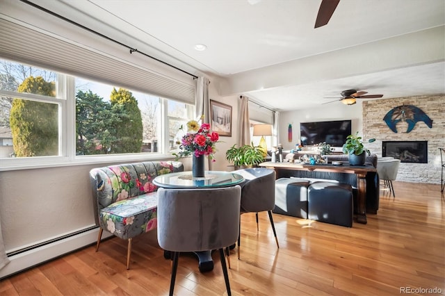 dining room with baseboard heating, a fireplace, and light hardwood / wood-style floors