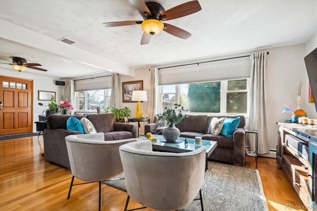 living room with beamed ceiling, light wood-type flooring, and ceiling fan