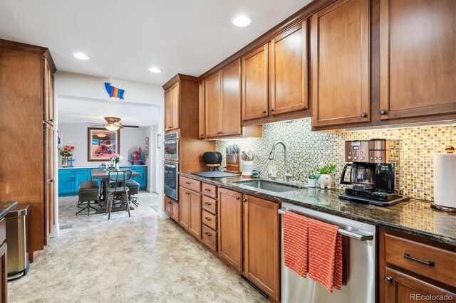 kitchen featuring dark stone counters, sink, ceiling fan, decorative backsplash, and appliances with stainless steel finishes