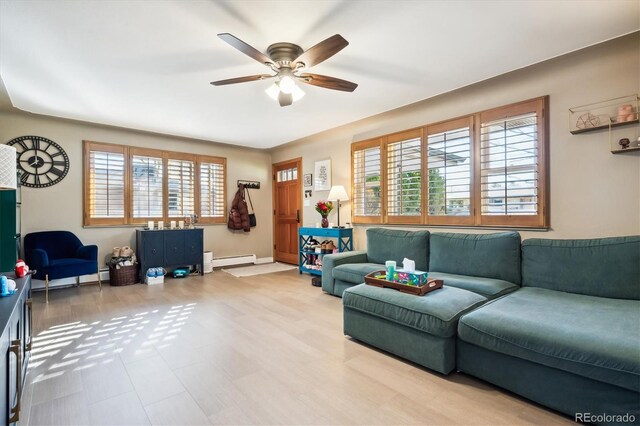 living room with baseboard heating, ceiling fan, and a healthy amount of sunlight