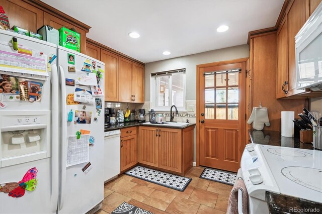 kitchen with backsplash, sink, a healthy amount of sunlight, and white appliances