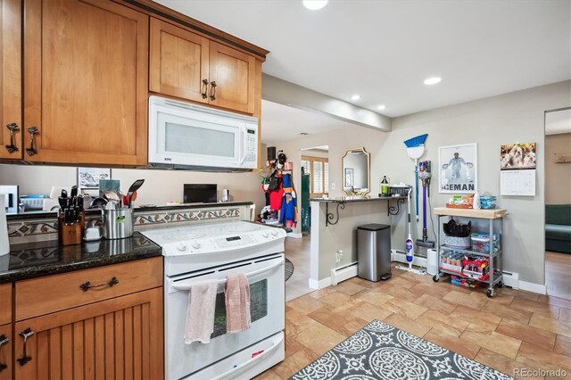 kitchen with white appliances, baseboard heating, and dark stone counters