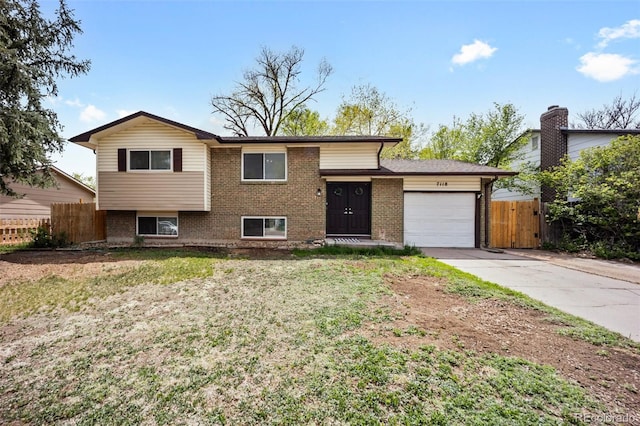 7118 Metropolitan St, Colorado Springs, CO 80911 - split level home featuring a garage, a front lawn, fence, brick siding, and concrete driveway