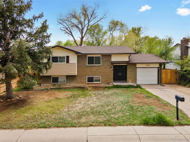 7118 Metropolitan St, Colorado Springs, CO 80911 - split level home featuring a garage, fence, driveway, and a front lawn