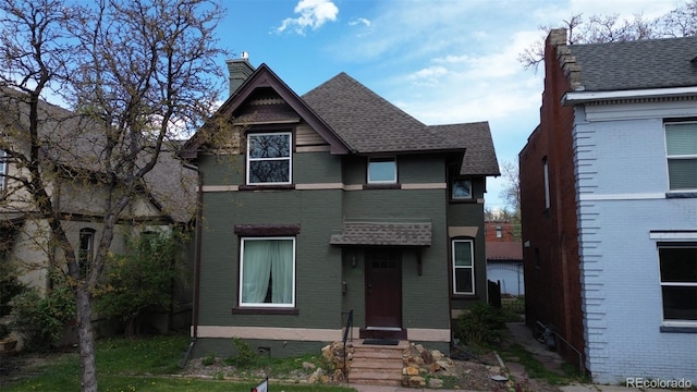 victorian-style house featuring roof with shingles, a chimney, entry steps, and brick siding