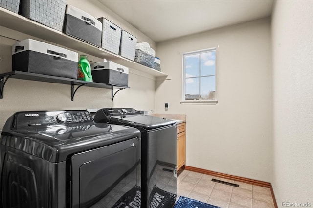 laundry room featuring cabinets, light tile patterned flooring, and washer and dryer