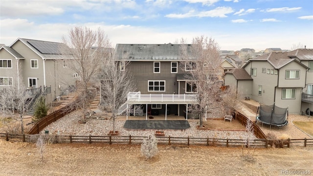 rear view of property featuring a patio, a deck, and a trampoline