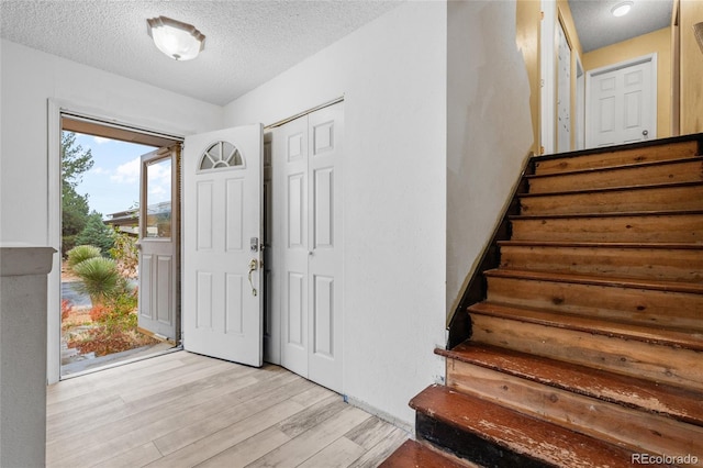 foyer entrance with a textured ceiling and light wood-type flooring