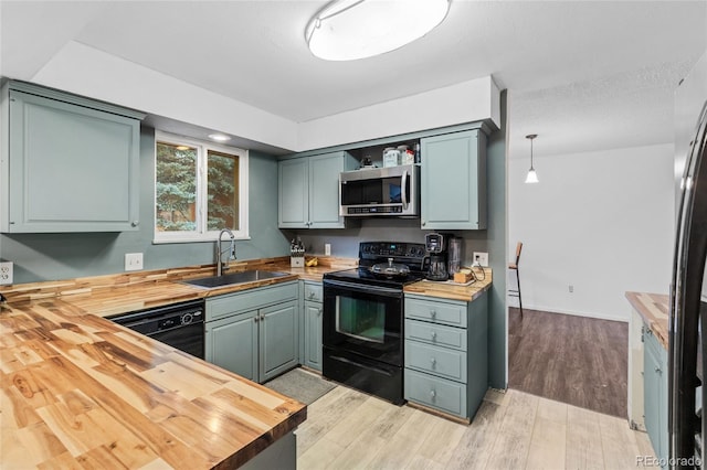 kitchen featuring black appliances, sink, and butcher block countertops