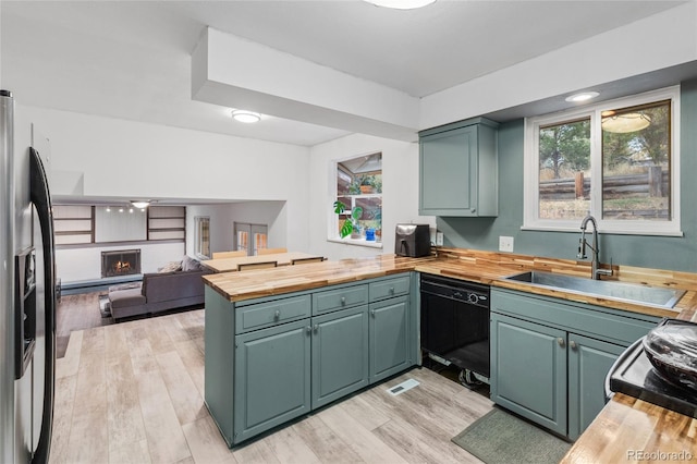 kitchen with stainless steel fridge with ice dispenser, dishwasher, plenty of natural light, sink, and butcher block countertops