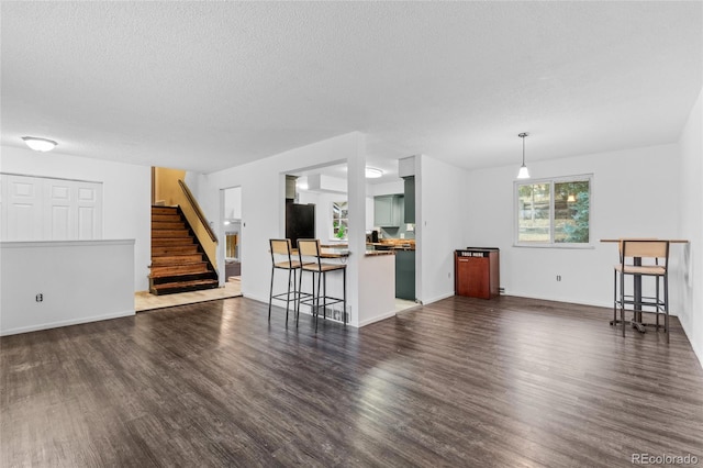 unfurnished living room with a textured ceiling and dark hardwood / wood-style flooring