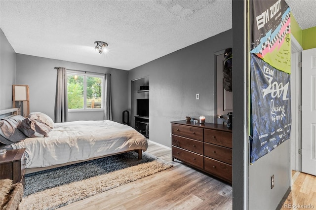 bedroom featuring light hardwood / wood-style flooring and a textured ceiling