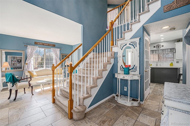 staircase with a high ceiling and baseboards