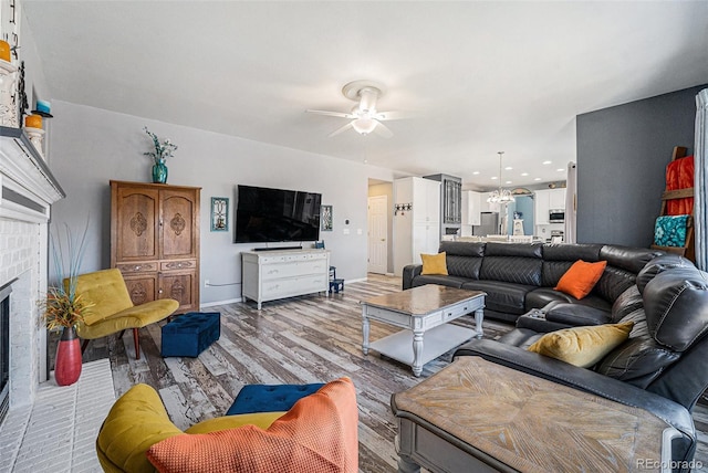 5224 Snow Goose St, Brighton, CO 80601 - living area featuring ceiling fan with notable chandelier, a brick fireplace, baseboards, and wood finished floors