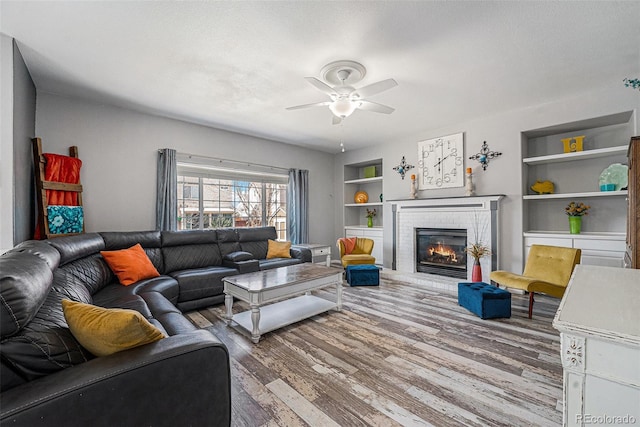 5224 Snow Goose St, Brighton, CO 80601 - living area featuring built in features, a ceiling fan, wood finished floors, a textured ceiling, and a brick fireplace