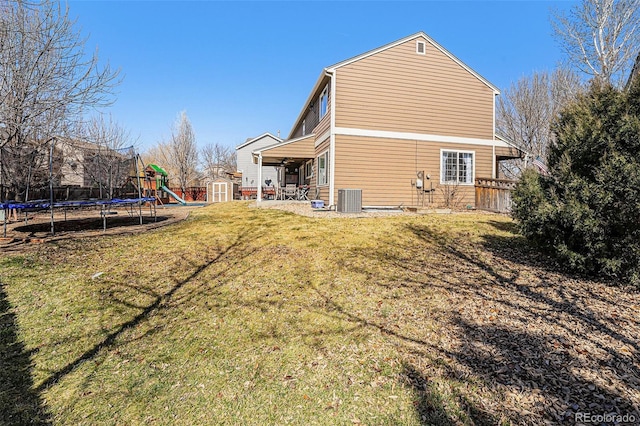 5224 Snow Goose St, Brighton, CO 80601 - back of property featuring central AC unit, a playground, a lawn, a trampoline, and a patio area