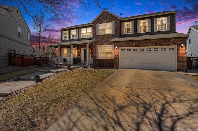 traditional-style home featuring brick siding, covered porch, concrete driveway, an attached garage, and fence