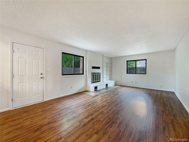 1460 Belmont Dr, Longmont, CO 80503 - unfurnished living room with a textured ceiling, built in features, wood finished floors, and a fireplace