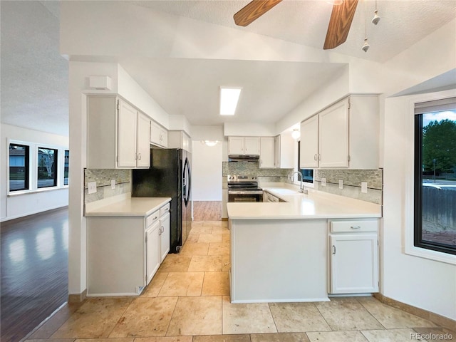 1460 Belmont Dr, Longmont, CO 80503 - kitchen with stainless steel range with electric cooktop, freestanding refrigerator, decorative backsplash, light countertops, and a textured ceiling